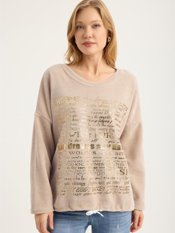 Blonde woman wearing a beige ribbed blouse with gold lettering "My Wish For" and jeans"