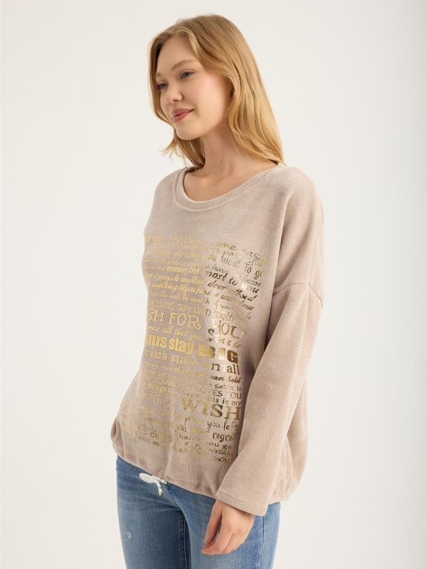 Blonde woman wearing a beige ribbed blouse with gold lettering "My Wish For" and jeans"