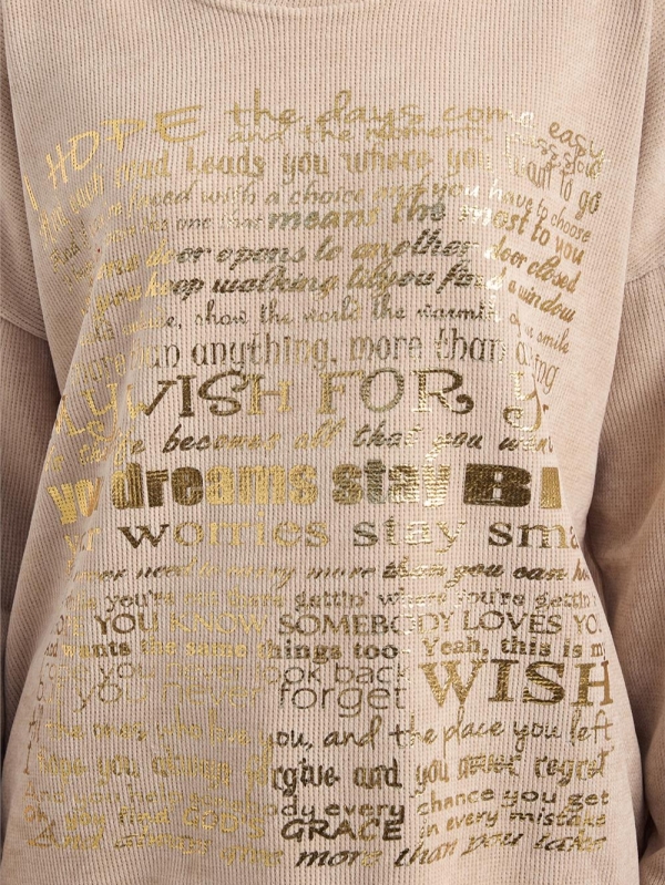 Blonde woman wearing a beige ribbed blouse with gold lettering "My Wish For" and jeans"