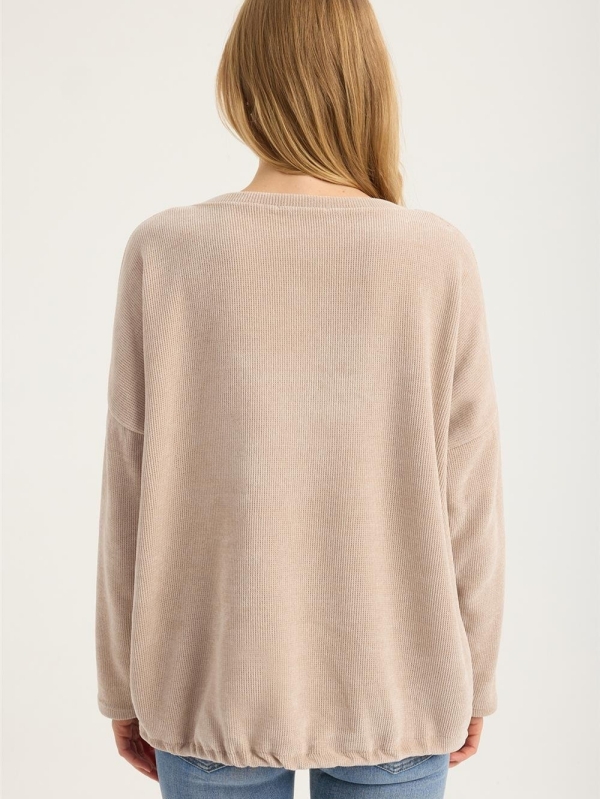 Blonde woman wearing a beige ribbed blouse with gold lettering "My Wish For" and jeans"