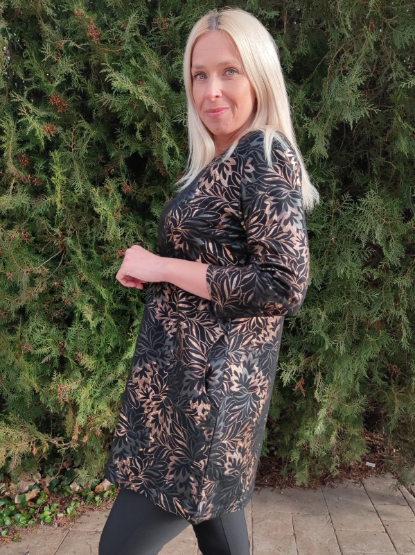 Жена облечена в черна туника със златни нюанси и зелен фон