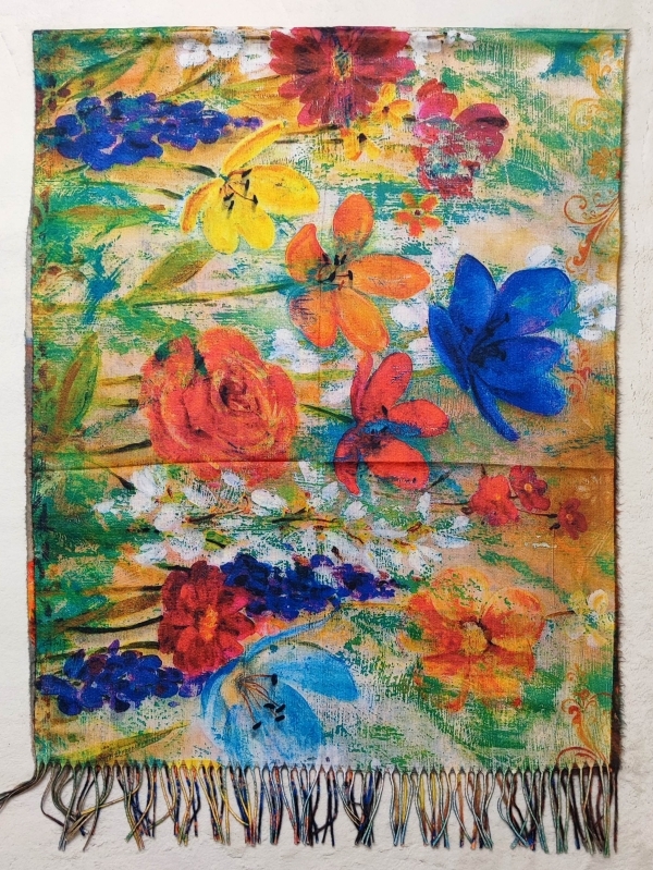 Close-up of an artistic women's scarf - bright floral motifs and flowers in a painterly style with fringe.