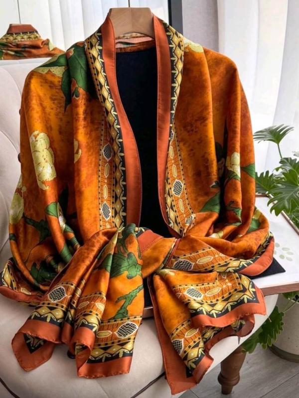 Long women's scarf made of polyester in orange with a print of yellow flowers and green leaves, casually draped