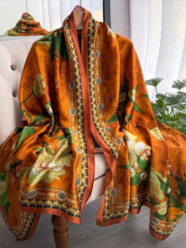 Long women's scarf made of polyester in orange with a print of yellow flowers and green leaves, casually draped