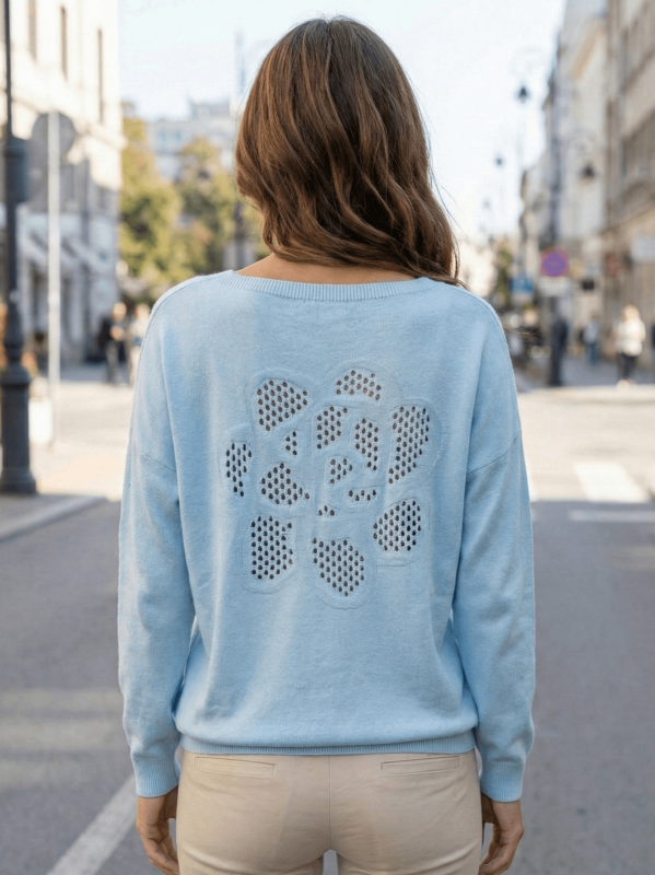 Back of a light blue women's sweater with large floral perforation.