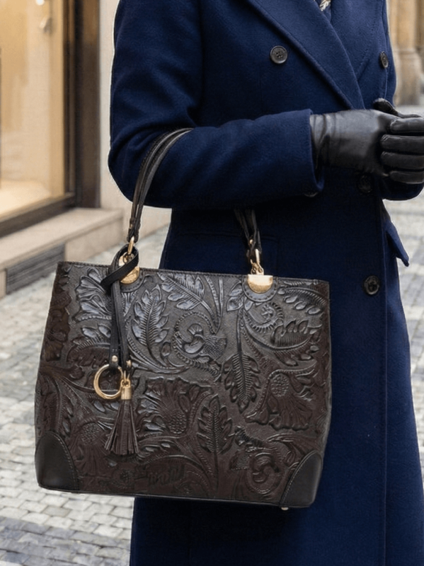 Дама с елегантно палто, носеща тъмно кафява чанта от естествена кожа с флорален принт, стилна ежедневна визия