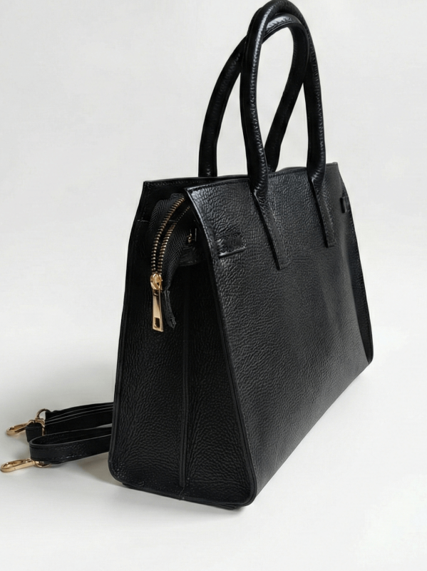 Side profile of a black leather bag, showing the depth and gold zipper.