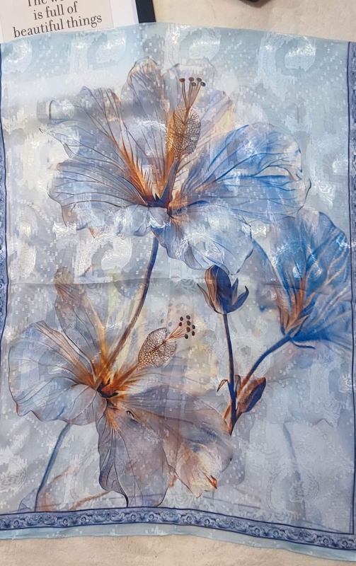 Детаил на флорален принт с големи цветя върху прозрачен син шал от коприна.