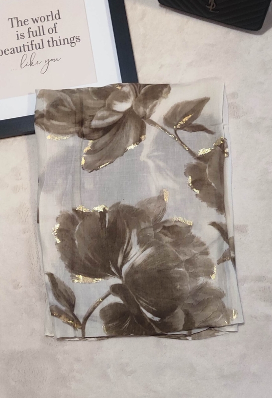 Сгънат бял шал с принт на големи бежови рози и златен кант.