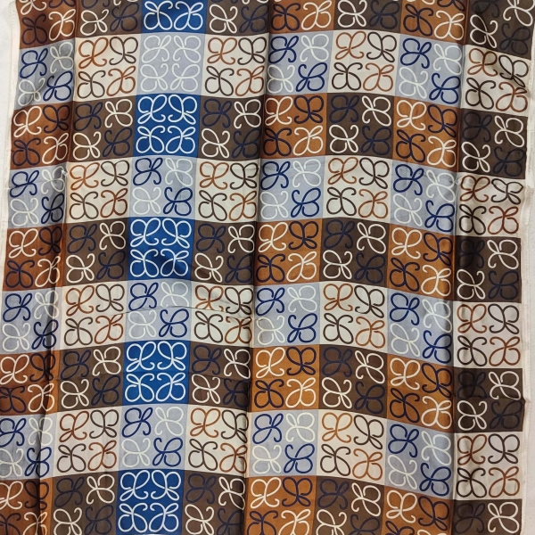 Texture of a satin scarf with a repeating geometric motif in brown, blue and white.