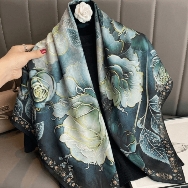 Elegantly draped double-faced women's scarf made of viscose and silk with a print of large roses in the blue-green range.