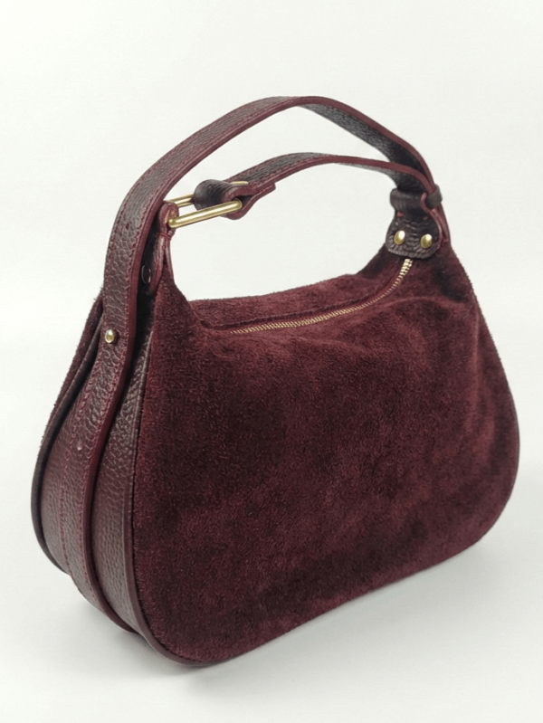 Elegant women's handbag made of natural suede in burgundy color, side view with focus on the leather details and metal elements.