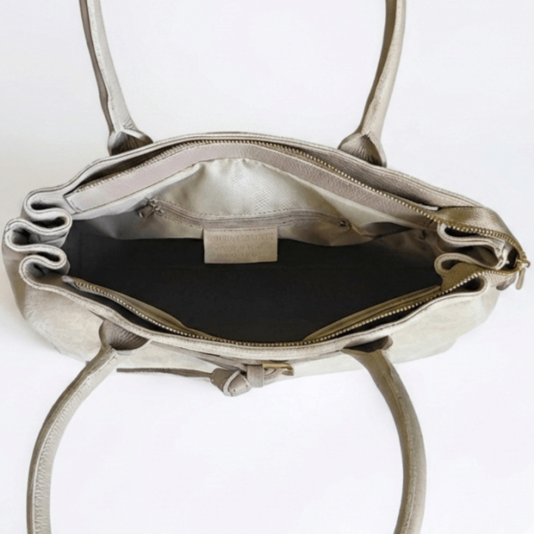 Вътрешно разпределение на италианска дамска чанта в светло бежово, показващо основно отделение с цип и допълнителни джобове.