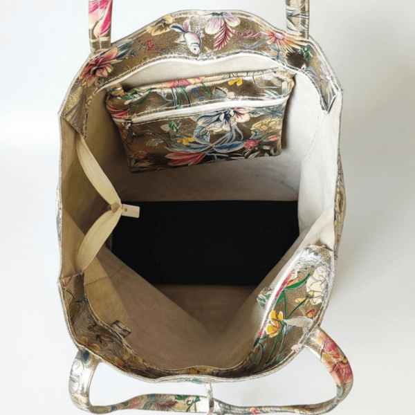 Вътрешно разпределение на голяма дамска чанта тип торба, показващо просторно основно отделение и прикрепен практичен вътрешен джоб с цип със същия флорален дизайн.