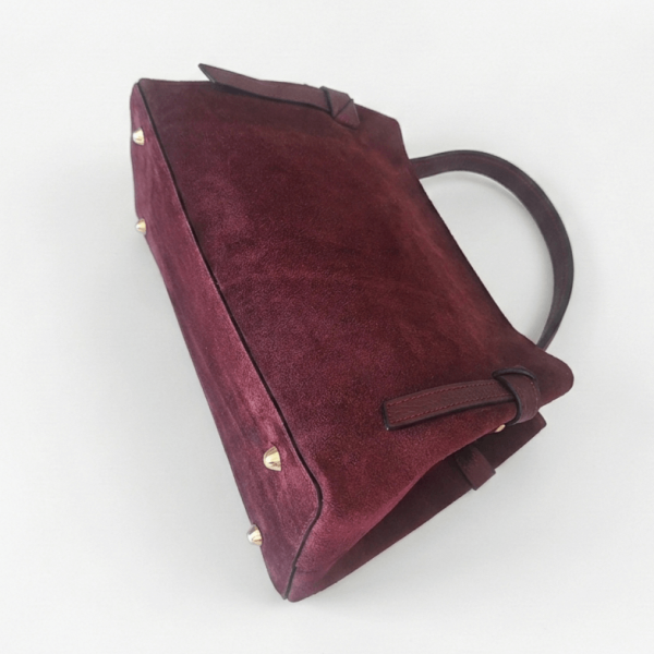 Elegant burgundy bag made of natural suede with a trapezoidal shape, decorative leather knots and a fine handle