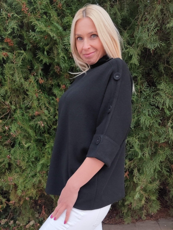 Detail of decorative buttons on the short sleeve and shoulder of a black women's sweater