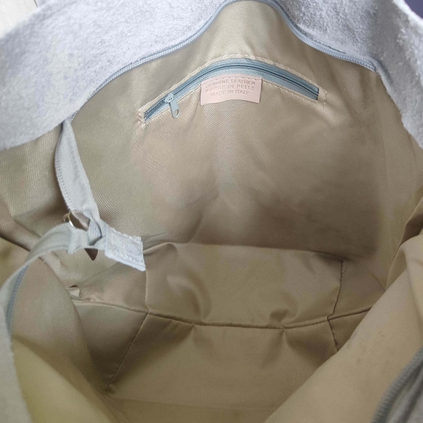 Вътрешност на сива велурена чанта с бежова платнена подплата и етикет от естествена кожа "Made in Italy".