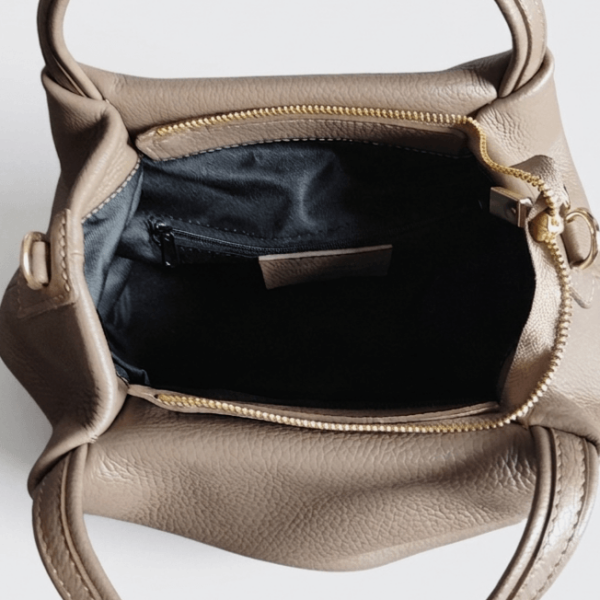 Open dark beige handbag, showing a spacious inner compartment with black lining, leather logo and a small practical zip pocket.
