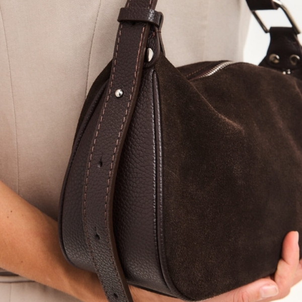 Близък план на края на регулируемата кожена дръжка с метални отвори и щифт за три различни дължини.