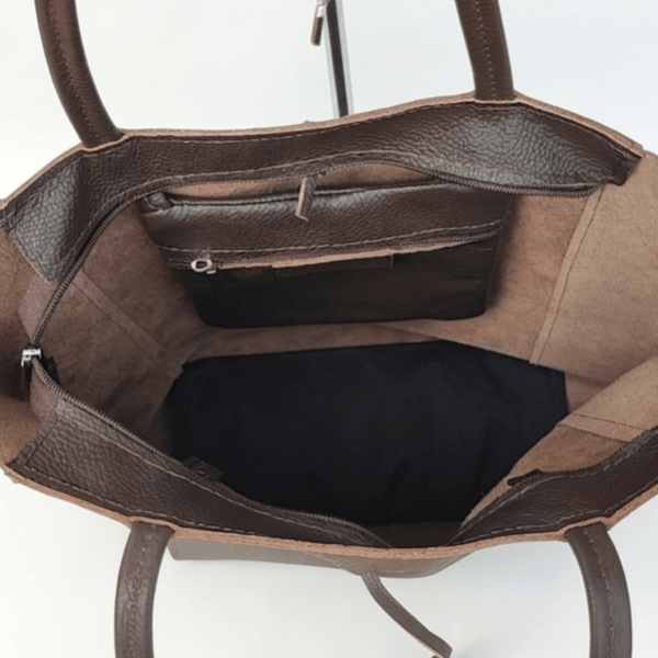 Interior compartment of a brown leather tote bag with a built-in zip pocket and an authentic unlined leather lining.