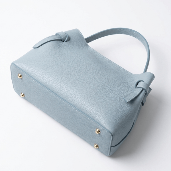 Дъно на светлосиня дамска чанта с предпазни метални крачета от златист месинг