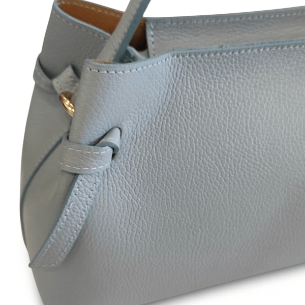 Близък кадър на зърнеста текстура от естествена кожа и декоративен детайл на светлосиня чанта