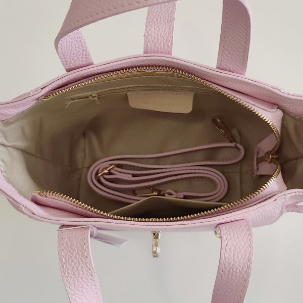 Interior of a pink Italian bag with pockets and a long leather strap tucked inside