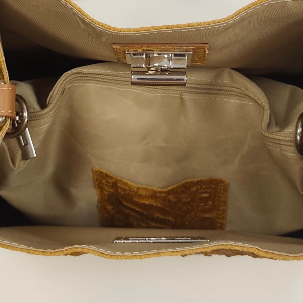 Lining and metal clasp on a mustard-colored suede handbag
