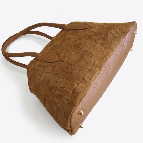 Smooth leather bottom of a light brown bag with gold-tone protective feet.
