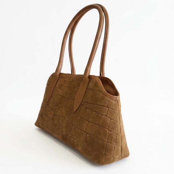 Side view of an elegant light brown suede shoulder bag with leather handles.