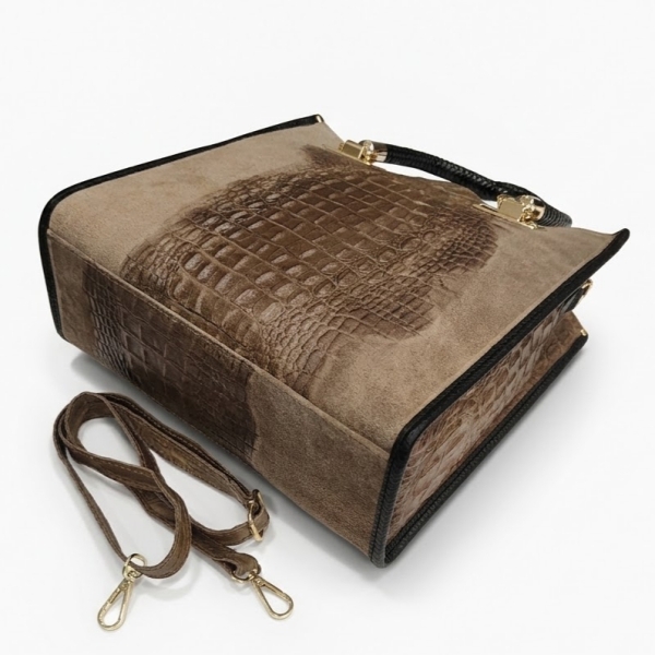 Detail of a beige women's handbag with a crocodile print, gold-tone metal hardware, and a structured base.