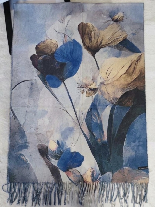 Detailed view of an unfolded women's cashmere scarf featuring an abstract floral print in blue and beige, finished with long fringes.