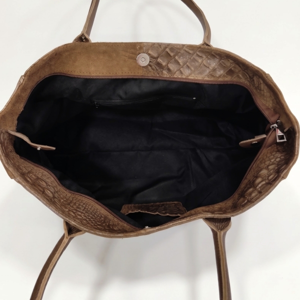 Top view of an open brown leather bag, showing a black lining, a zippered pocket, and a magnetic closure.