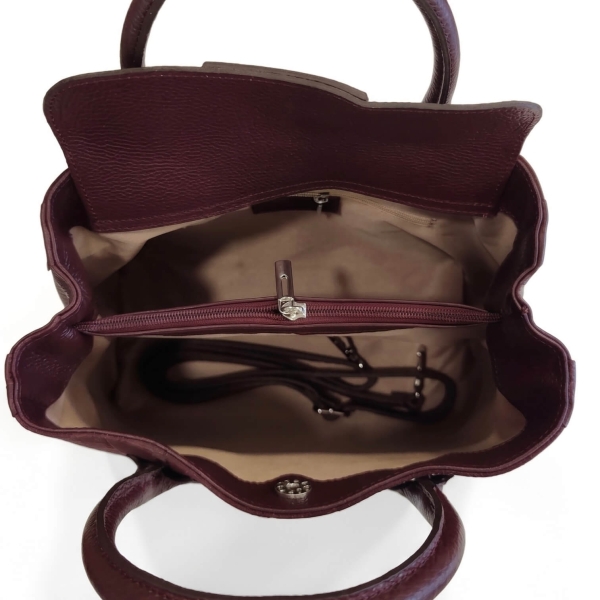 Top-down view of the interior of a bag with three compartments, a central zippered section, and a light-colored lining.