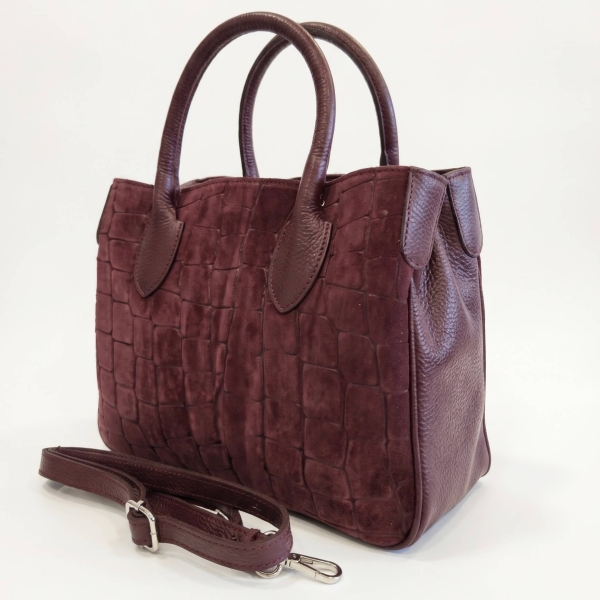 Side angle of an Italian women's handbag in burgundy, made of genuine leather and suede, featuring an adjustable shoulder strap.